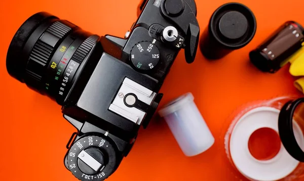 来自类似时代的旧相机 背景橙色 周围有胶卷和高脚杯 — 图库照片