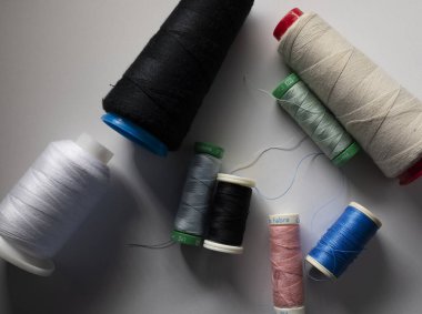 Çeşitli renk ve boyutlarda dikiş için iplik ruloları, beyaz, siyah, mavi, pembe, yeşil, beyaz arkaplan