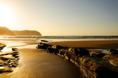 Güçlü bir kaya hattı ve altın ışığı olan sahil.