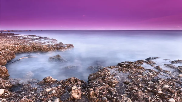 Soft and smooth sea on the rock ground and purple sky