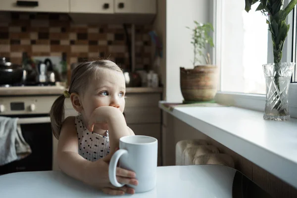 Niña linda sentada a la mesa en la cocina —  Fotos de Stock