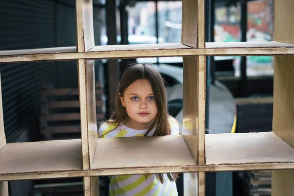 Una chica guapa mirando por detrás de una estructura en forma de jaula. Concepto de juego —  Fotos de Stock