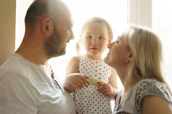 Anne, baba ve küçük kız. Arka ışıkta yakın çekim portre.