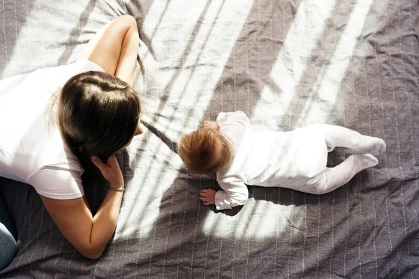 Mère avec son fils nouveau-né couché sur le lit dans les rayons du soleil — Photo