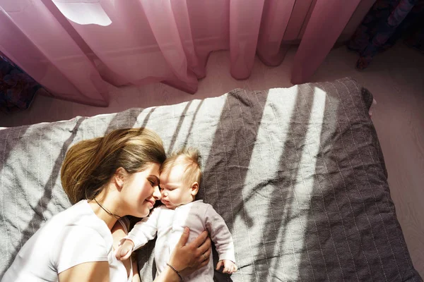 Mère avec son fils nouveau-né couché sur le lit dans les rayons du soleil — Photo