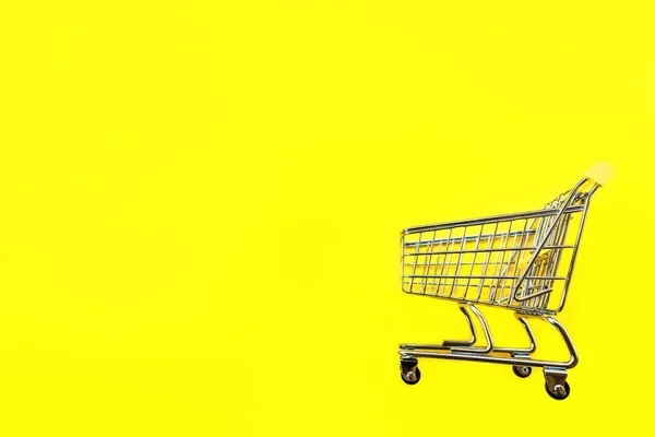 Carro de juguete para productos sobre fondo amarillo. Lugar para el texto . —  Fotos de Stock