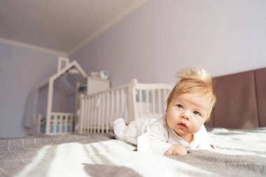 Yeni doğmuş bir bebek yatakta kreşte midesinde yatıyor..