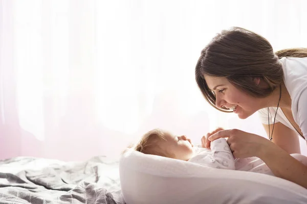 Mère avec son fils nouveau-né couché sur le lit dans les rayons du soleil — Photo