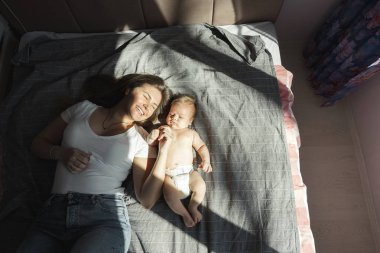 Yeni doğan oğluyla birlikte anne güneş ışığı Altında yatakta yatıyordu. 