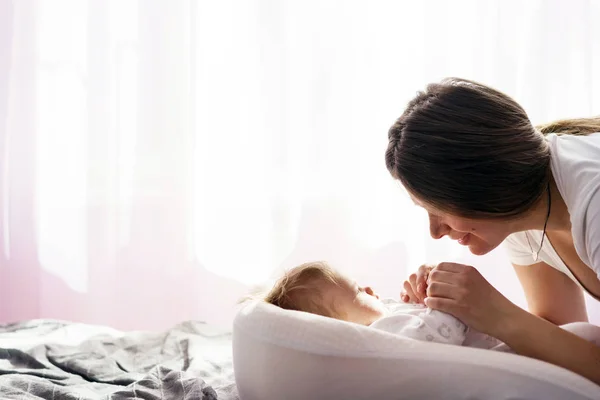 Un bebé recién nacido está acostado en la cama y la madre le sostiene las manos —  Fotos de Stock