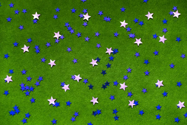 Blue and silver sparkles stars on a bright green background.