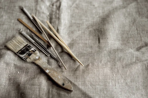Herramientas de arcilla sobre lienzo gris. Cepillo, palos de madera, pilas, espátulas de metal —  Fotos de Stock