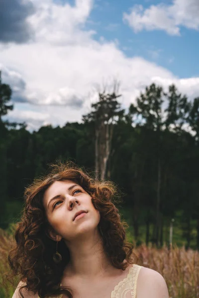 Όμορφη νεαρή σγουρά μαλλιά κοκκινομάλλα κορίτσι σε ένα φόντο του δάσους — Φωτογραφία Αρχείου
