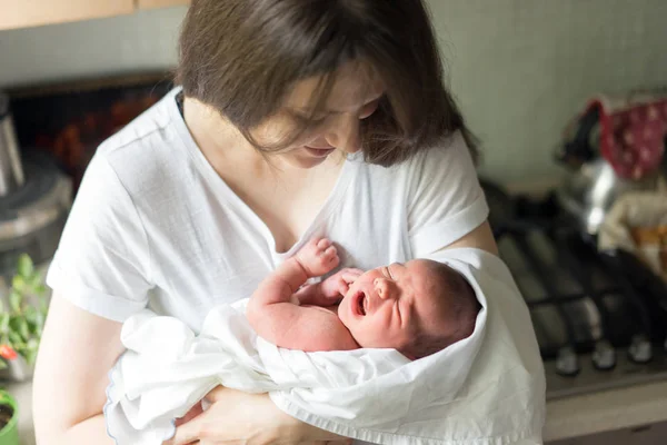 Une mère avec un nouveau-né dans les bras l'allaite dans la cuisine . — Photo