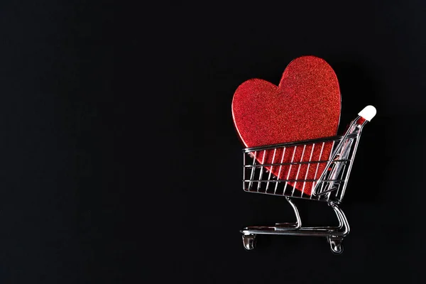 Vörös szív alakú ajándékdoboz a bevásárlókosárban egy fekete háttér. — Stock Fotó