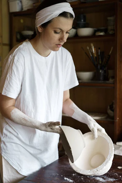 Beautiful young woman takes out a clay bowl from a mold