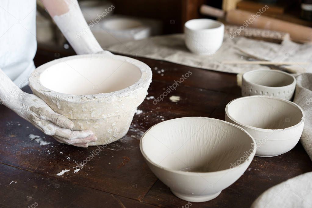 Female hands hold a bowl for casting clay products