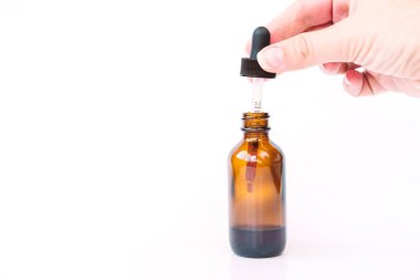 Berrak kahverengi şişeye serum bırakan bir kadının eli