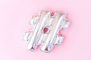 Pembe arka planda gümüş şişme hashtag işareti. Minimalist düz yatıyordu.