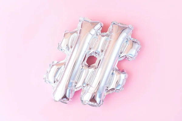 Pembe arka planda gümüş şişme hashtag işareti. Minimalist düz yatıyordu.
