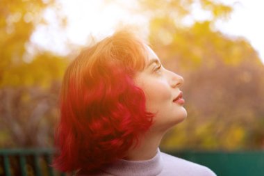 Kırmızı boyanmış saçlı ve sonbahar sarı yaprakları arka plan ile güzel kadın. 