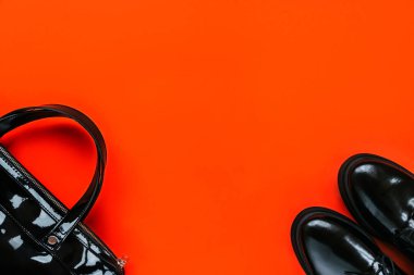 Kırmızı arka planda siyah ayakkabı ve çanta. Kara Cuma konsepti