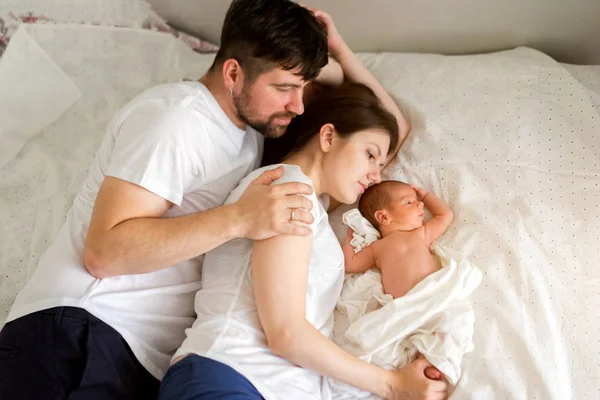Baba, anne ve yeni doğan oğlu evde yatakta yatıyorlar. 