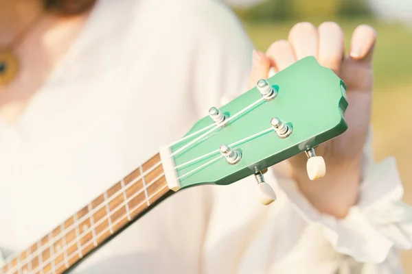 Ukulele iplerini tunlayan kadın. Müzik aletinin perde tahtası