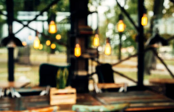 Blurred cafe background with glass walls and beautiful yellow decorative bulbs. No focus.