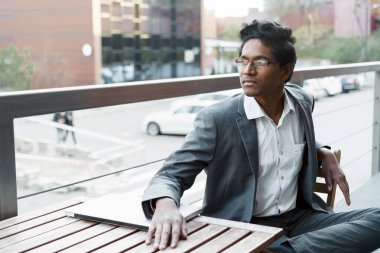 Beyaz gömlekli ve takım elbiseli yakışıklı Hintli genç oturuyor. 