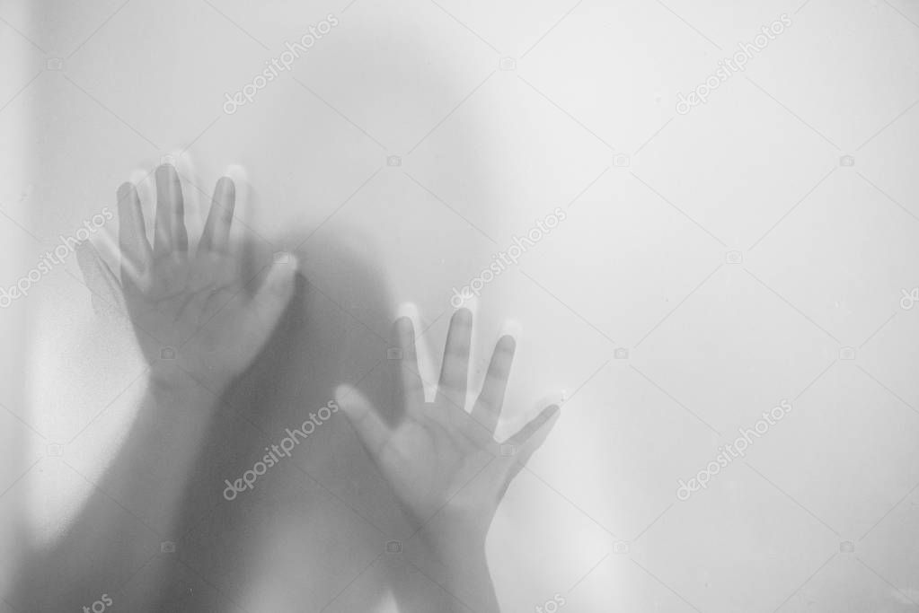 Shadow hands of the woman behind frosted glass.Blurry hand abstraction.Halloween background.Black and white picture