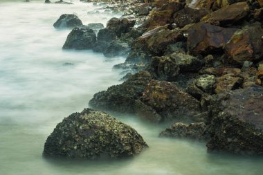 Köpüklü dalgalar Tayland bir kayalık sahil karşı sabah zamanında sıçramasına ile uzun pozlama deniz manzarası