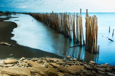 Uzun pozlama deniz manzarası Bambu duvar kıyıya dalgalar deniz internet korumak için. Tayland