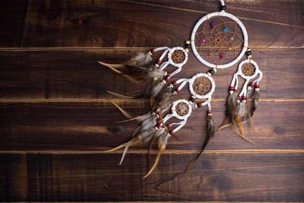 Dream catcher with feathers threads and beads rope hanging spiritual folk american native indian amulet isolated on brown wooden textured background.Concept prevent evil in Halloween