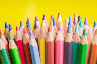 Okula geri dön. Renkli kalemler sarı arka planda yan görünüm oluşturur.