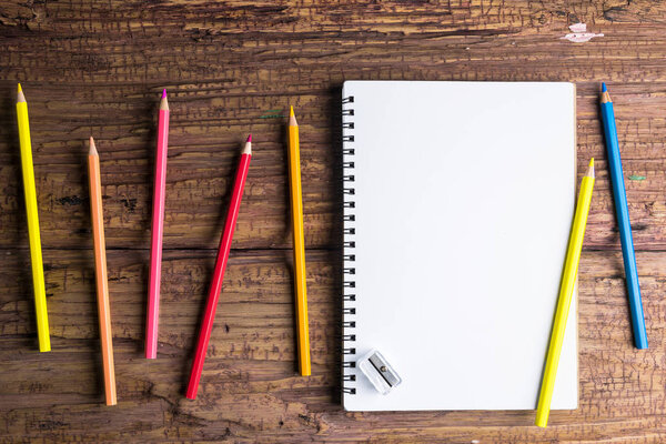 Вид сверху на белую бумагу блокнота Blank и лакированную цветную ручку на коричневом деревянном фоне с пространством для сообщения

