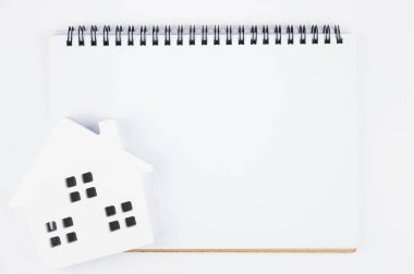 Kopya alanı mesajınız için beyaz zemin üzerine üstten görünüm boş defter beyaz kağıt ve kağıt ev modeli... Emlak kavramı