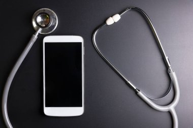 Mobil bir akıllı telefon, siyah arka plan üzerinde izole kompozisyon yüzey üzerinde sağlık stetoskop aracı. Sağlık Güvenlik kavramı kontrol.