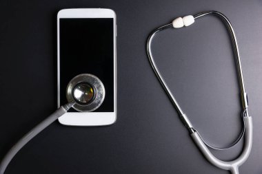 Mobil bir akıllı telefon, siyah arka plan üzerinde izole kompozisyon yüzey üzerinde sağlık stetoskop aracı. Sağlık Güvenlik kavramı kontrol.
