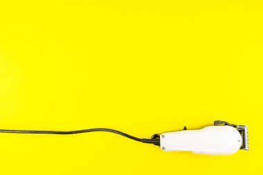 Sarı arka plan üzerinde beyaz elektrik makası berber. Kuaför