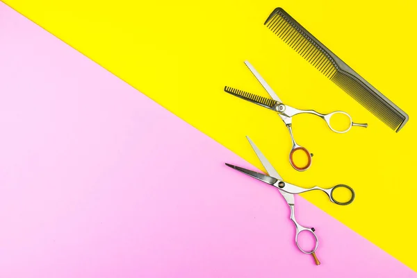 Stylish Professional Barber Scissors and comb on yellow and pink