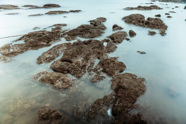 Dlouhá expozice fotografie vln na kamenných plážových vodách hrana AB — Stock fotografie