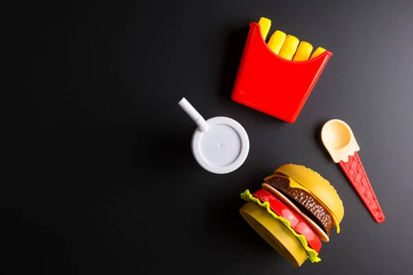 Plastic burger, French fries Fast food on black background. Chil