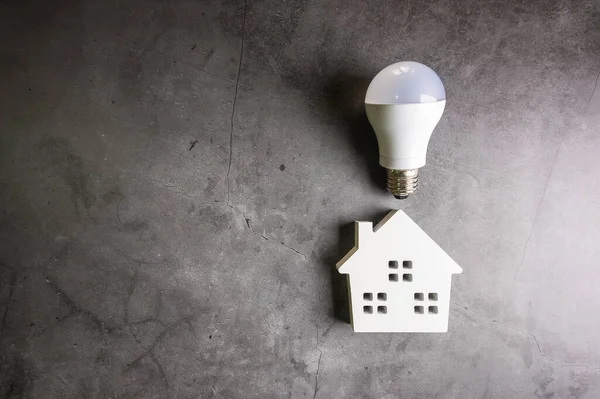House and light bulbs on stone pattern background with copy spac