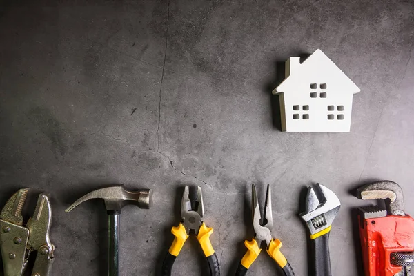 Casa de madera y herramientas de construcción sobre fondo de patrón de piedra — Foto de Stock