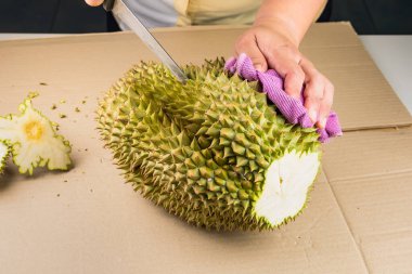 Ahşap masada yakın plan bir bıçakla Durian meyvesi kesen bir kadın. Durian, Tayland 'da popüler meyvelerden biridir..