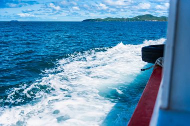 Su mavisi okyanus su sıçratır ve deniz yolunda tekne, dalgalar geminin kenarına vurur.