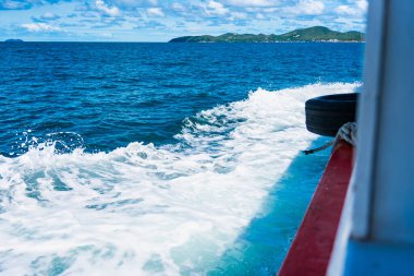 Su mavisi okyanus su sıçratır ve deniz yolunda tekne, dalgalar geminin kenarına vurur.