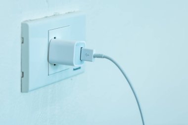 Evin duvarına yakın çekim elektrik prizi takılı. Şarj aleti yuvaya bağlı..