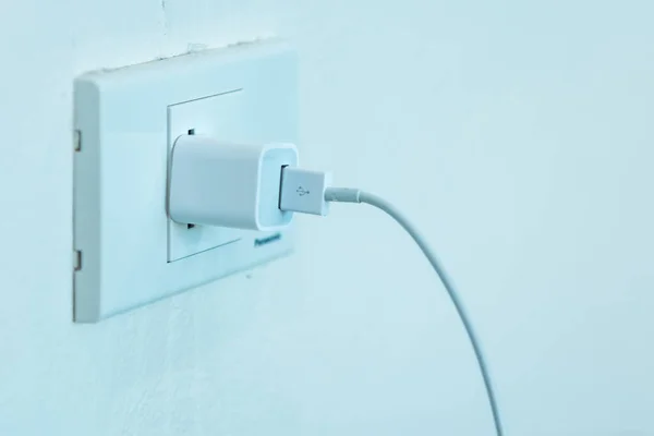 Close-up power outlet attached to the wall of the house. Charger attached to the socket.